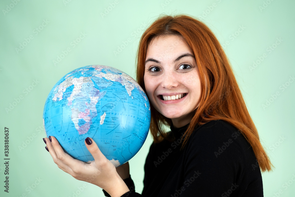 Portrait of a happy young woman holding geographic globe of the world in her hands. Travel destination and planet protection concept. Portrait of a happy young woman holding geographic globe of the world in her hands. Travel destination and planet protection concept.