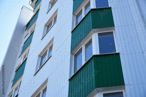facade of a new multi-storey building with white and green metal siding  many Windows