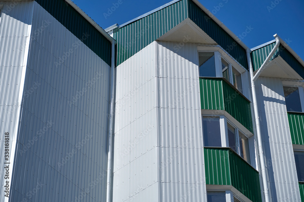 facade of a new multistory building with white and green metal siding, many Windows facade of a new multistory building with white and green metal siding, many Windows