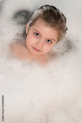 Sweet little girl in the bath foam