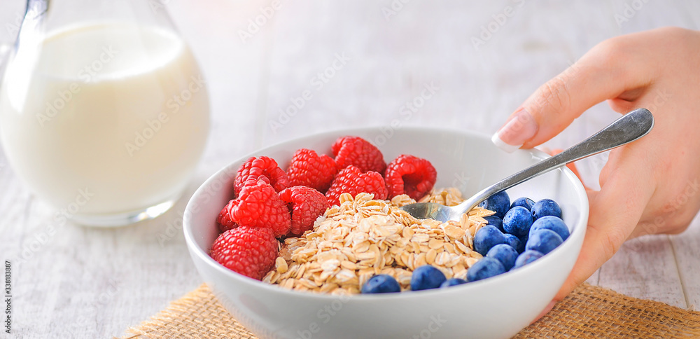 Top view of oat flakes with forest fruits. Raspberries and blueberries in white plate with oat flake Top view of oat flakes with forest fruits. Raspberries and blueberries in white plate with oat flake