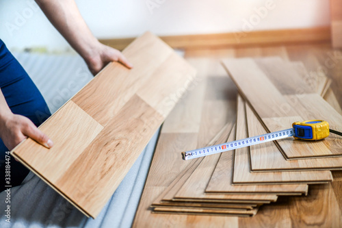 Worker hands installing timber laminate floor in modern house. Wooden floors renovation photo