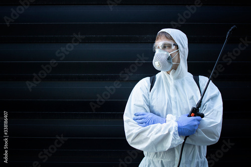 Portrait of professional exterminator holding sprayer with chemicals for pest control. Copy space provided. photo