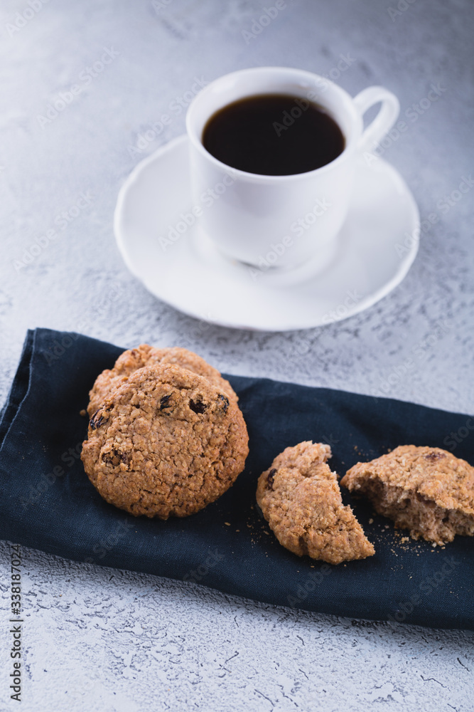 Fototapeta premium White cup of coffee with oatmeal cookies and coffee maker, breakfast concept, selective focus
