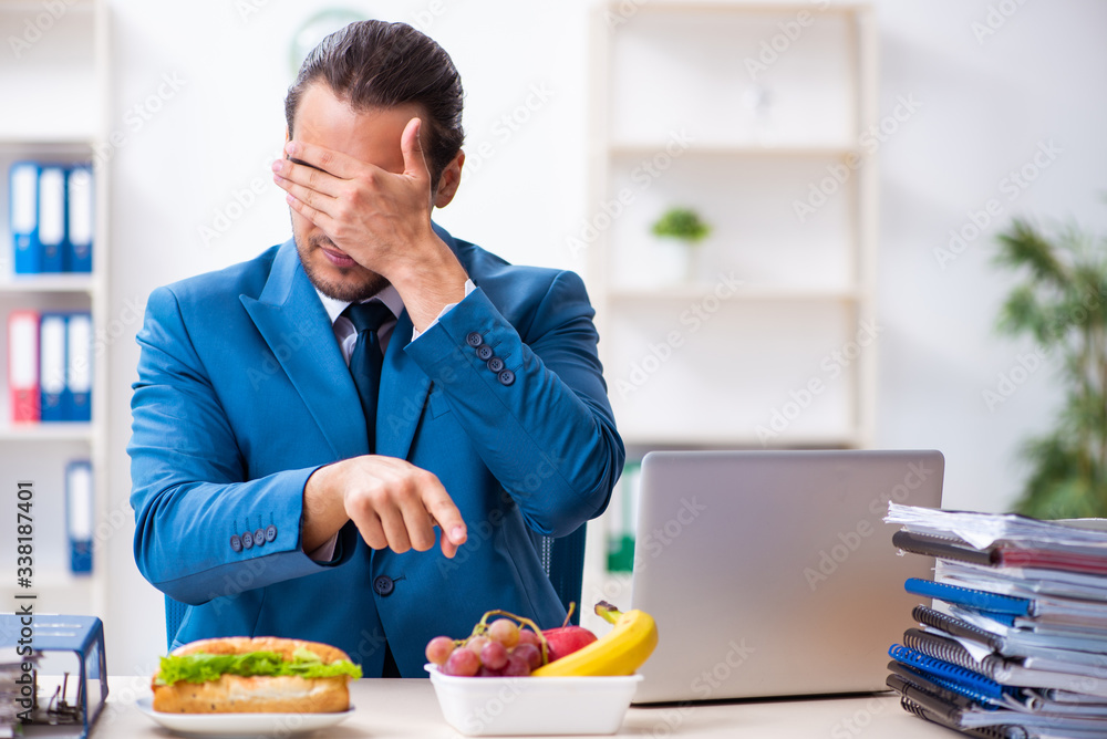 Young male employee having breakfast at workplace Young male employee having breakfast at workplace