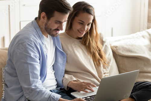 Photography Happy young family couple sitting on couch, using computer together at home