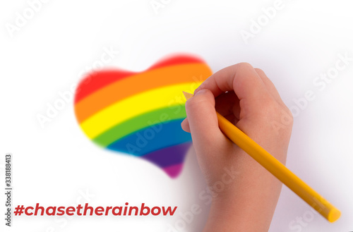 The concept of the pursuit of the rainbow. A hand with a pencil draws a heart in rainbow colors. inscription chasetherainbow photo