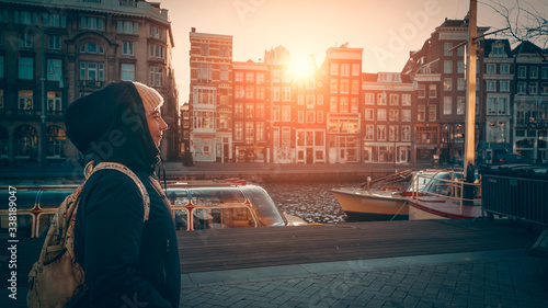 Photography Cute young woman walks along water canal in Amsterdam at sunset sunlight, Netherlands
