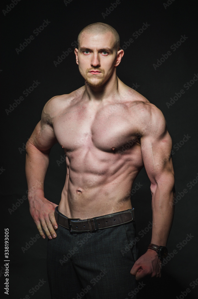 Sporty sexy man stands Topless on a dark background. Sports, beauty