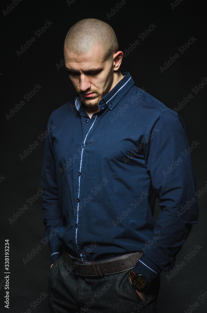 A stylish, bald young man stands on a dark background in the category. Business, Finance A stylish, bald young man stands on a dark background in the category. Business, Finance