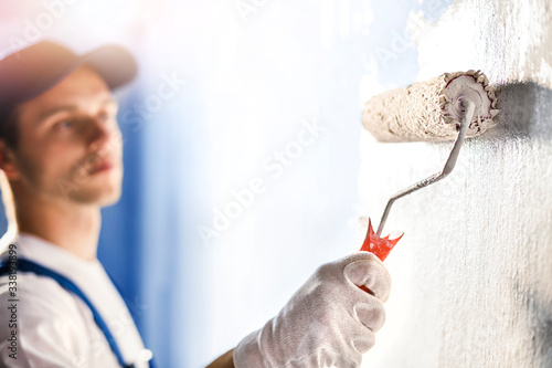 Painter painting a wall with paint roller.