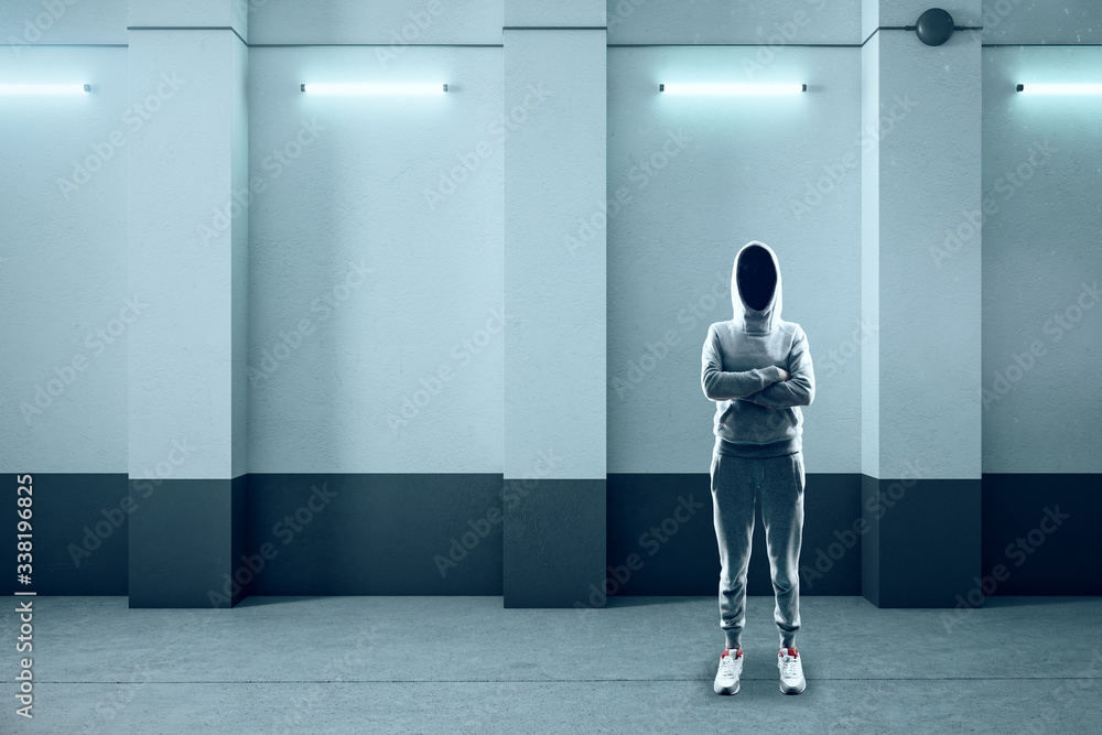 Hacker standing in abstract illuminated concrete interior Hacker standing in abstract illuminated concrete interior