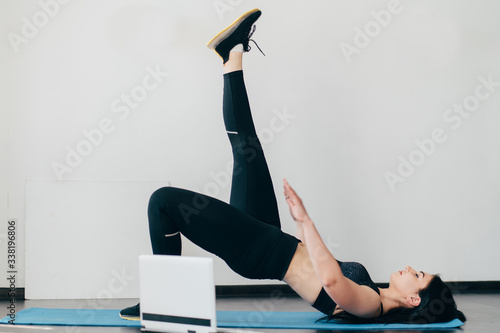 Home training, fitness, motivation concept. Young fit woman doing sport exercises with online guide in her living room.