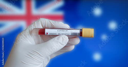 COVID-19 Pandemic Coronavirus concept ; Close-up of a Positive COVID-19 blood test sample tube with Flag of Australia at background. Blood testing for diagnosis new Corona virus infection.