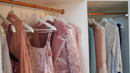 Close up of hangers with different clothes in wardrobe.