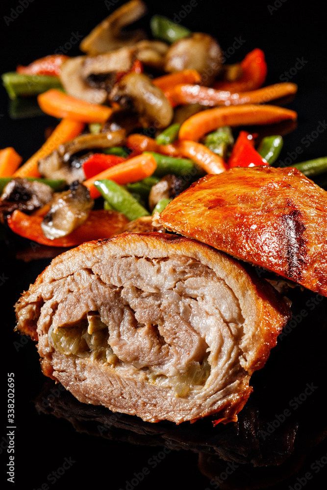 Roasted meat with caramelised sauce. Cutted piece of meat with juicy reflections. Grilled vegetables on sides. Black background Roasted meat with caramelised sauce. Cutted piece of meat with juicy reflections. Grilled vegetables on sides. Black background