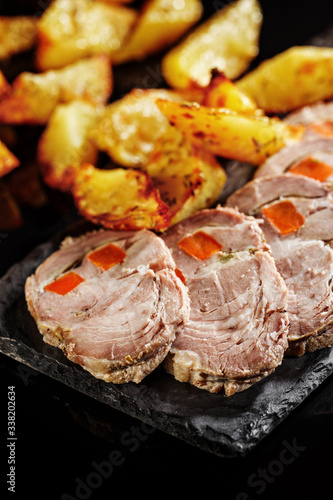Close-up of grilled pork meat with fried potato. Black background