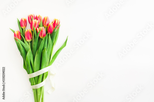 Beautiful spring bouquet of pink tulips flowers with white ribbon on white background