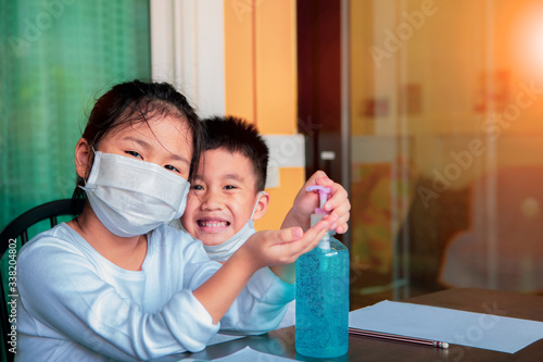 asian children wearing face protection mask and  cleaning hand by alcohol gel photo