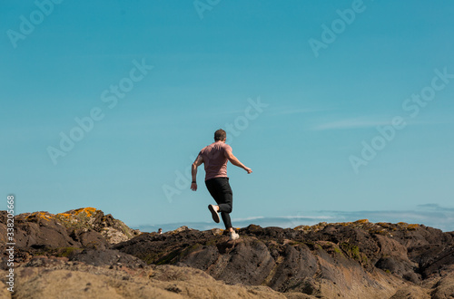 Man running on rocks on Scottish coast