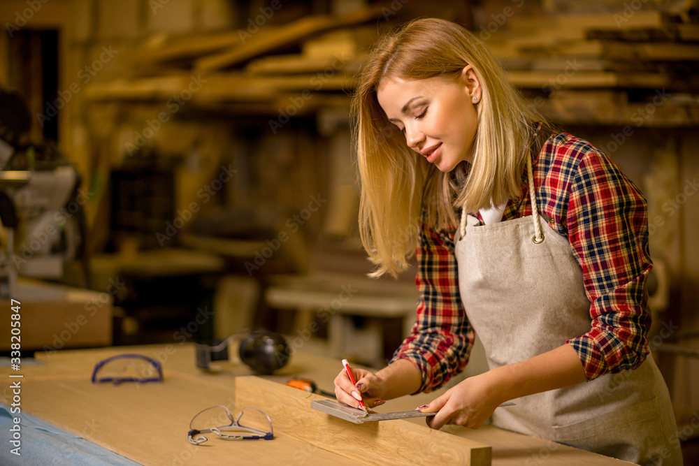 Fototapeta premium portrait of professional woodworker making marks on wooden piece, woman make handmade furniture in workshop, enjoy working alone