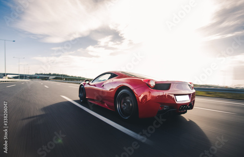 Fototapeta Naklejka Na Ścianę i Meble -  Red luxury model sport car view from behind on the highway
