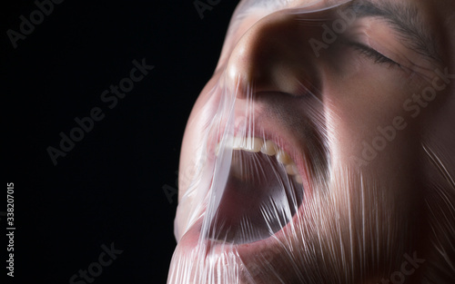 Konstfotografi close-up portrait of a plastic bag on the face asphyxiation
