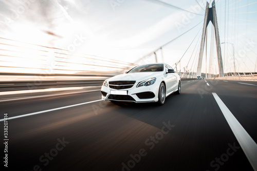 White business class sedan car driving on the highway over the bridge in the daytime