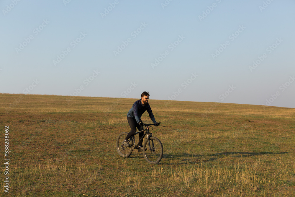 Cyclist in shorts and jersey on a modern carbon hardtail bike with an air suspension fork standing on a cliff against the background of fresh green spring forest Cyclist in shorts and jersey on a modern carbon hardtail bike with an air suspension fork standing on a cliff against the background of fresh green spring forest