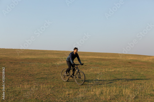 Cyclist in shorts and jersey on a modern carbon hardtail bike with an air suspension fork standing on a cliff against the background of fresh green spring forest