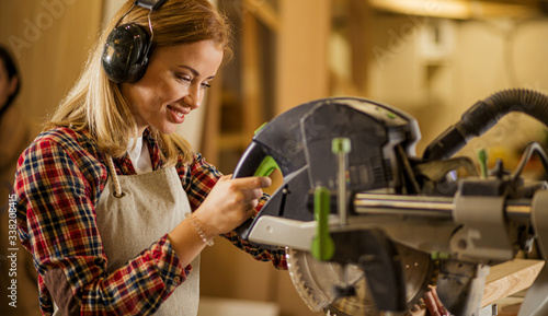 portrait of young caucasian carpenter working in workshop listening to music, woman enjoy making wooden furniture, woman isolate herself from noisy sounds in factory