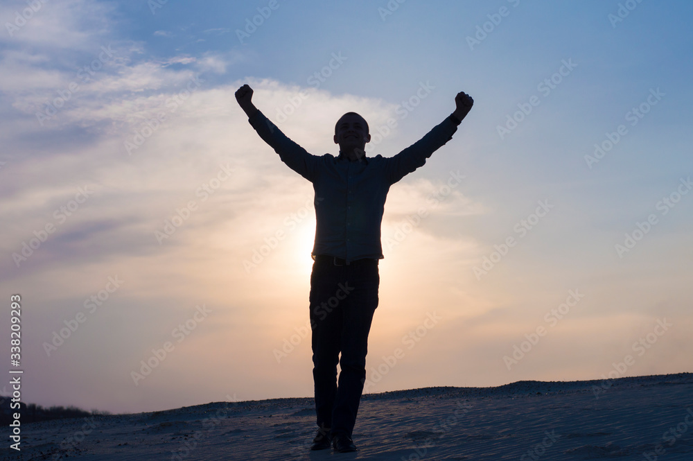 silhouette photo of guy with hands up at sunset time on sky background