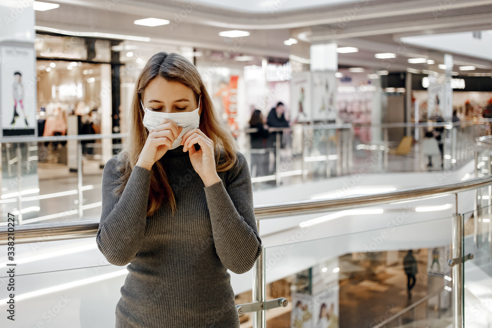 a girl sneezes in a protective mask at a shopping center