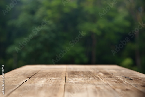 Brown wood table top on a green blur abstract background