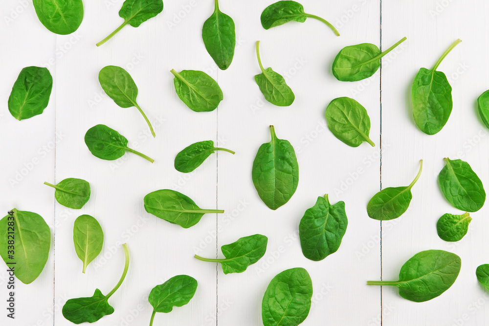 Green spinach leaves on white wooden table background. Healthy vegan food trend. Eco-conscious concept. Top view.