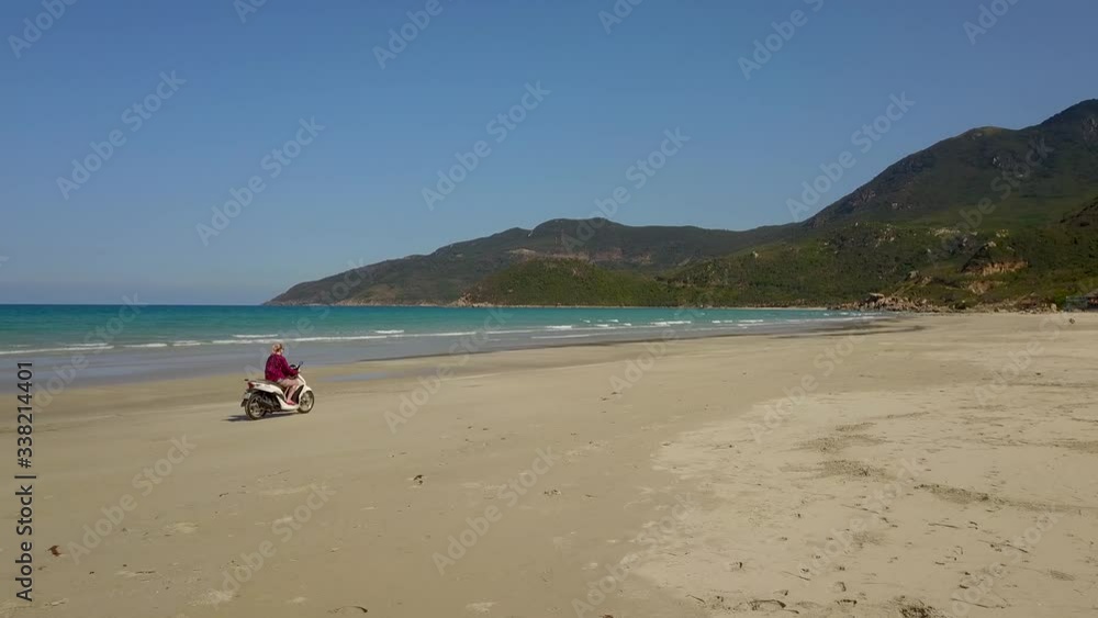 a flying camera takes pictures of a girl riding a motorbike in the sand on the beach. Nha Trang Vietnam a flying camera takes pictures of a girl riding a motorbike in the sand on the beach. Nha Trang Vietnam