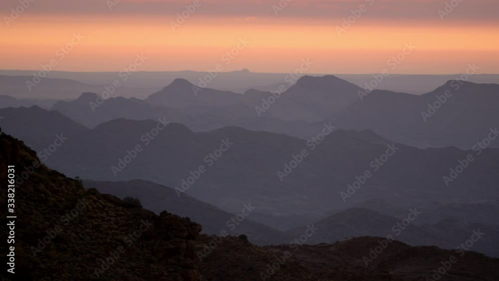 Panning shot across a seemingly endless mountain range under the pink and orange colours of the sunset. Panning shot across a seemingly endless mountain range under the pink and orange colours of the sunset.