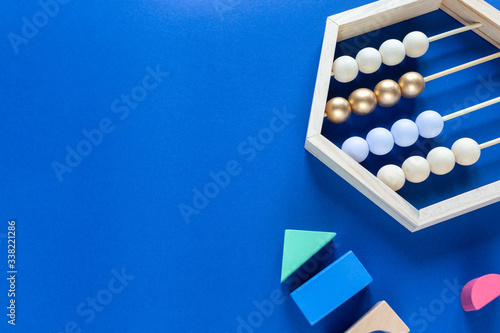 Colorful math wooden abacus, blocks on classic blue background. Interesting, fun math for kids, preschooler. Education, back to school concept