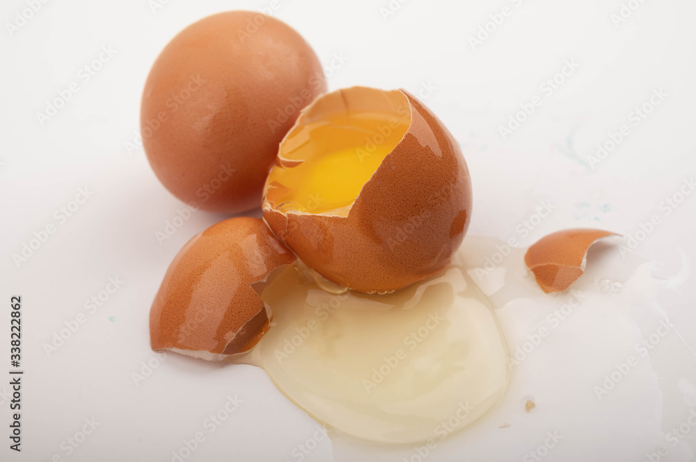 Broken chicken egg and chicken eggs scattered on a white background background. Close up. Broken chicken egg and chicken eggs scattered on a white background background. Close up.