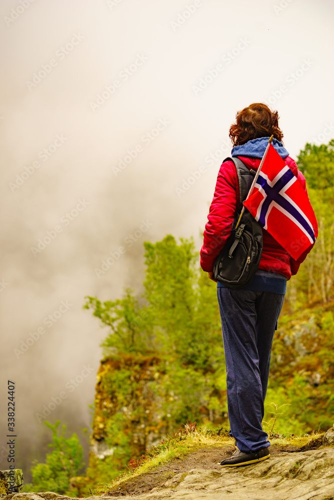 Tourist with norwegian flag in hazy mountains