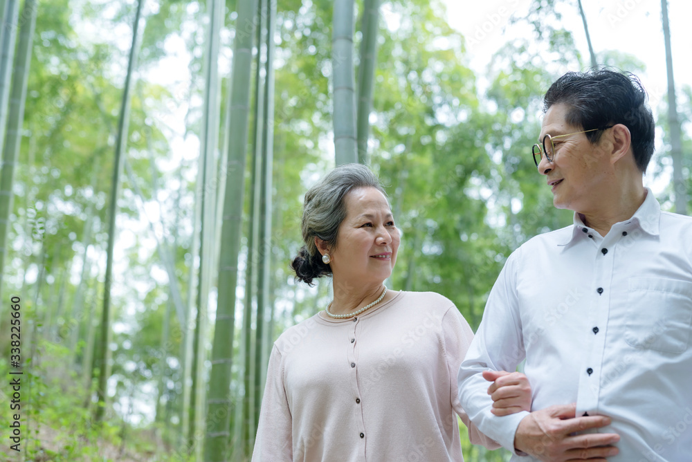 An elderly Asian couple walking in a bamboo forest An elderly Asian couple walking in a bamboo forest