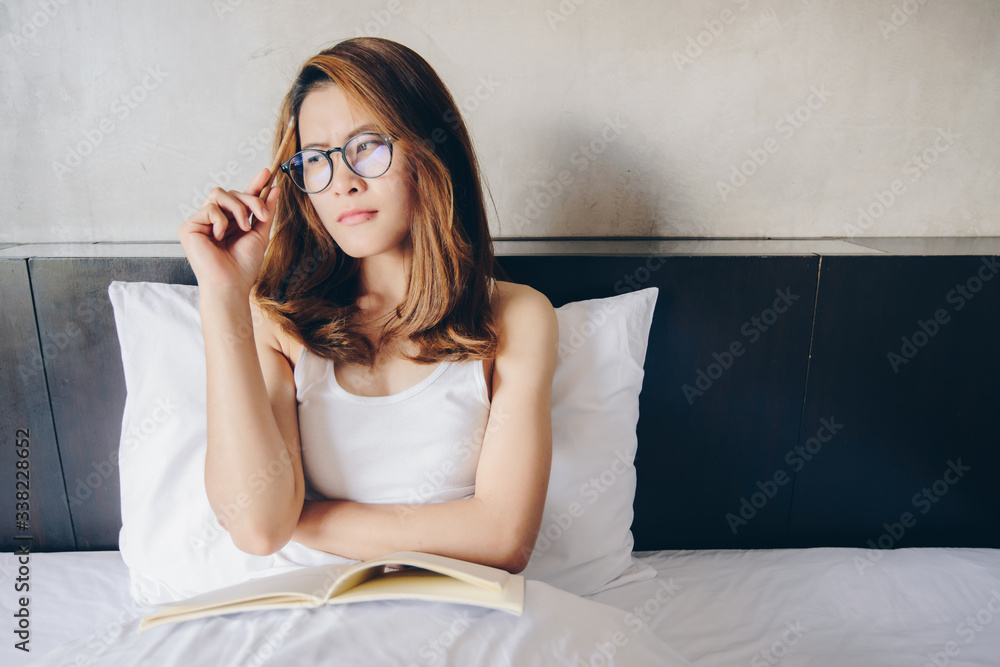 Portrait of young happiness Asian woman sitting on bed, holding a notebook and pencil on her hands, ready to work or writing something from home. Conceptual of woman lifestyle. Portrait of young happiness Asian woman sitting on bed, holding a notebook and pencil on her hands, ready to work or writing something from home. Conceptual of woman lifestyle.