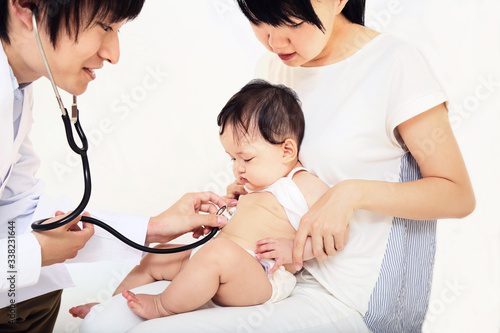 白衣を着た男性医者に聴診器で診察を受ける赤ちゃん。