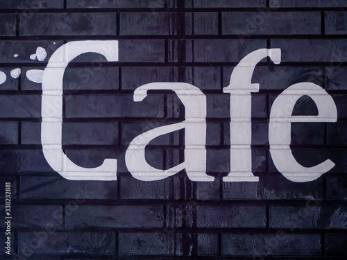 Close Up of Black Brick Wall with Word Cafe in Worn White Paint