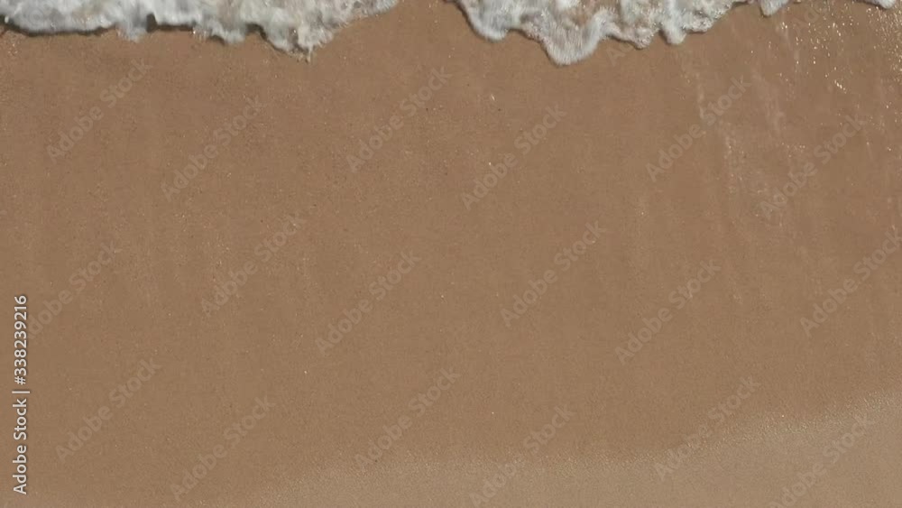 AERIAL: Beautiful Generic Tropical Beach Overhead Shot, bird's eye view of ocean waves crashing against an empty beach from above 