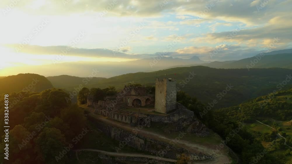 Beautiful orange sunset rays of sun Anacopia Fortress New Athos ancient stone stronghold on top of high mountain. Best natural landscape cityscape. Picturesque Abkhazia mountains horizon. Flight above Beautiful orange sunset rays of sun Anacopia Fortress New Athos ancient stone stronghold on top of high mountain. Best natural landscape cityscape. Picturesque Abkhazia mountains horizon. Flight above
