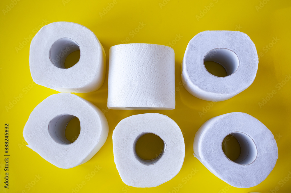 Pile of rolls of white toilet paper on a yellow background, top view Pile of rolls of white toilet paper on a yellow background, top view