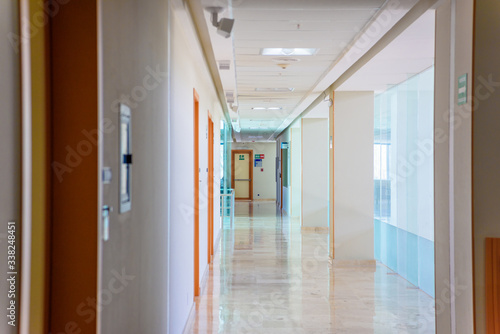 A huge brown door in a white corridor in a hospital.
