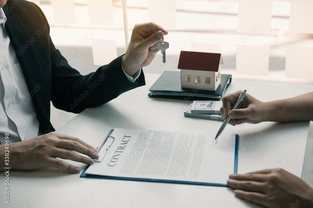 Hand of real estate agent passes the key to new homeowners in office with buyer house concept. Hand of real estate agent passes the key to new homeowners in office with buyer house concept.