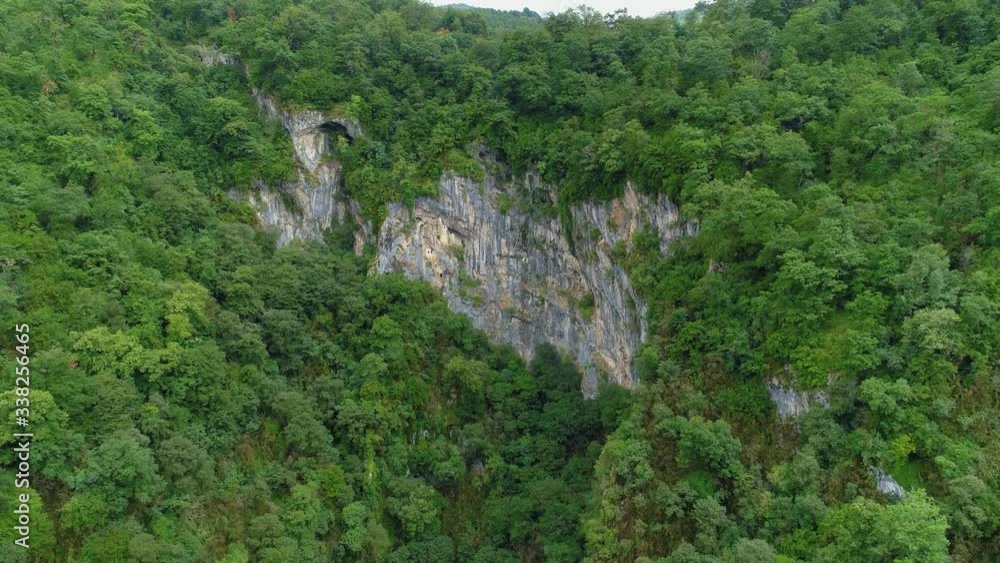 From above epic canyon сaucasian mountains. Rocky ancient monastery inside sheer cliff around green forest trees. Georgia historical unique attraction. Clouds fog on peaks natural landscape. Aerial From above epic canyon сaucasian mountains. Rocky ancient monastery inside sheer cliff around green forest trees. Georgia historical unique attraction. Clouds fog on peaks natural landscape. Aerial
